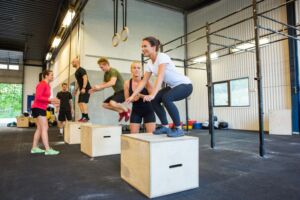 The image shows athletes engaged in barbell exercises within a functional training facility, featuring thick rubber flooring that provides superior shock absorption and a stable surface for lifting heavy weights. This durable rubber gym flooring enhances safety during high intensity workouts and is designed for optimal performance in commercial gym applications.
